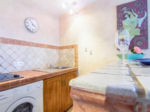 a kitchen with a washing machine and a clock on the wall at Apartment Les Carles by Interhome in Saint-Tropez +14 photos