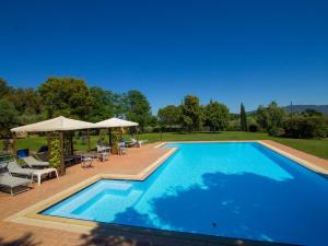 a swimming pool with chairs and umbrellas next to at Apartment Formula 1 by Interhome in Casa Fusi