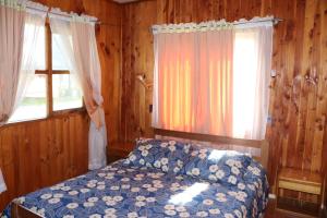 um quarto com uma cama e duas janelas em Cabañas Paihuén em Pucón