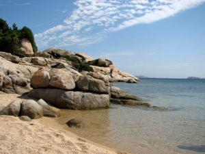 una playa con algunas rocas y el agua en Baia di Ulisse, en Porto Pozzo