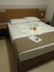 a bed with white sheets and a flower on it at ILHAS DO LAGO ECO RESORT in Caldas Novas +30 photos