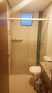 uma casa de banho com um chuveiro, um WC e uma janela. em ILHAS DO LAGO ECO RESORT em Caldas Novas