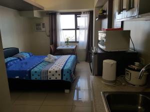 een kleine kamer met een bed en een keuken met een wastafel bij KC Studio 4 at Horizon 101 Cebu in Cebu City