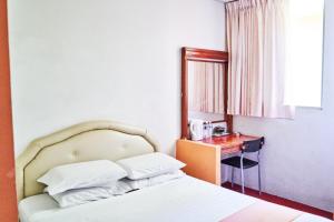 a bedroom with a bed with a desk and a window at Plaza Inn in Sibu