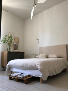 a white bedroom with a large bed and a table at l'autre maison in Penne-dʼAgenais