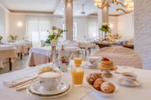 a table with cups and plates of food and drinks at Hotel Massimo in Marina di Cecina