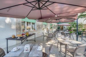 patio ze stołami, krzesłami i parasolami w obiekcie Hotel Massimo w mieście Marina di Cecina