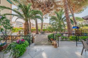 a courtyard with palm trees and a fountain at Hotel Massimo in Marina di Cecina