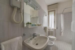a white bathroom with a sink and a toilet at Hotel Massimo in Marina di Cecina