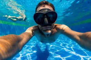 a man swimming in a swimming pool with a pair of goggles at Hotel Saraje in San Juan del Cesar