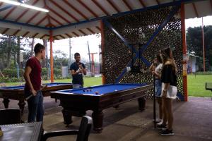 a group of people standing around a pool table at Hotel Campestre La Tata in Montenegro