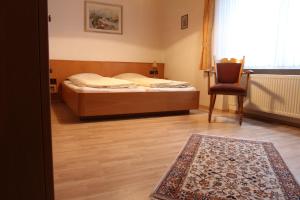 una camera con un letto, una sedia e un tappeto di Hotel Waldschlösschen a Füchten