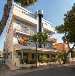 un gran edificio blanco con banderas en los balcones en Hotel Kennedy, en Rímini