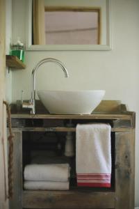 a sink in a bathroom with towels on a shelf at El Jardin, Eco Cabañas Boutique in San Alfonso