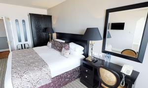 a hotel room with a bed and a mirror at Tynemouth Grand Hotel in Tynemouth