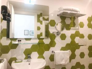 a green and white bathroom with a sink and a mirror at Casa Sorrentina in Sorrento