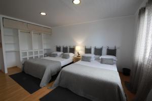 two beds in a room with white walls at Vista do Cais in Lagoa