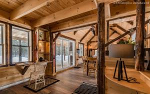 Cabaña de madera con sala de estar con mesa y sillas en Le Ross - Les Chalets Spa Canada, en La Malbaie