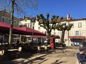 a street with tables and chairs and trees and buildings at Corps et graphi(qu)es in Périgueux