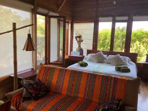 Chez Manany Galapagos Ecolodge في بْوُرتو فيلاميل: غرفة نوم بسرير واريكة ونوافذ