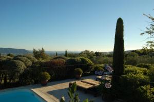 einen Garten mit einem Tisch, Bänken und Büschen in der Unterkunft Mas de la Beaume in Gordes