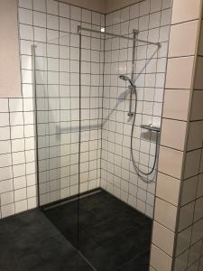een badkamer met een douche en witte betegelde muren bij Ferienwohnung Kirschholz in Schmelz