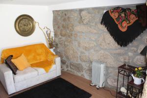 a living room with a couch and a stone wall at Casinha da Raposeira in Soajo