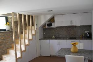 a kitchen with white cabinets and a counter top at Casinha da Raposeira in Soajo