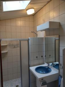 La salle de bains est pourvue d'un lavabo bleu et d'un miroir. dans l'établissement B&B De Blauwe Tulp, à Noord-Scharwoude