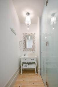 Porto Deluxe Apartments في بورتو: حمام مع حوض أبيض ومرآة