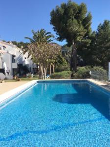 een blauw zwembad met bomen op de achtergrond bij Tranquil setting in Moraira