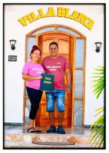 a man and a woman standing in front of a door at Hostal "Villa Blanca" in Caibarién