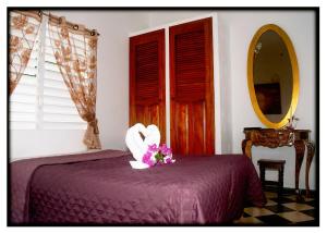 a bedroom with a bed with a purple bedspread and flowers at Hostal "Villa Blanca" in Caibarién