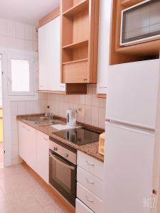 a kitchen with white cabinets and a sink at Apartamento Calipso in Salou