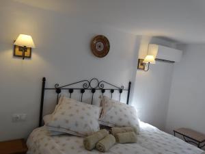 1 cama con 2 almohadas y reloj en la pared en B&B Cortijo Loma León, en Cútar