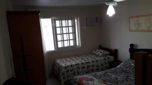 1 dormitorio con 2 camas y ventana en Pousada Rosa Norte, en Tramandaí