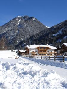 a lodge in the snow in front of a mountain at Residence Kahn in Santa Maddalena in Casies