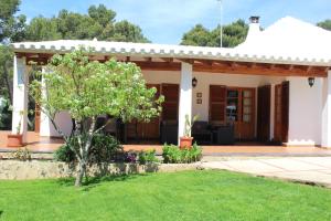 una pequeña casa blanca con un árbol en el patio en Villa Moll, en Cala Morell