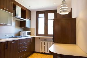 a large kitchen with wooden cabinets and a window at May Land Apartment in Szklarska Poręba