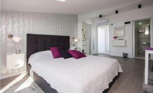 ein großes Schlafzimmer mit einem großen Bett mit lila Kissen in der Unterkunft Apartmani Riva in Rogoznica