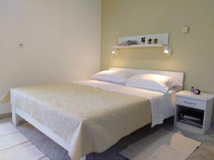 1 dormitorio con 1 cama blanca grande y mesita de noche en Apartments Anica, en Pula