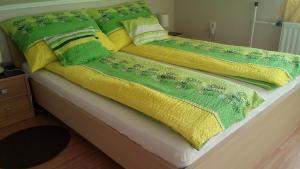 a bed with yellow and green blankets and pillows at Zöld Sziget Apartman in Gyula