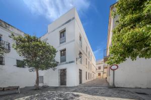 un edificio blanco con un árbol en una calle en Casa en Plaza de la Merced_Centro Flamenco_Cádiz, en Cádiz