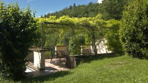 einen Garten mit einem Tisch, Stühlen und Bäumen in der Unterkunft Casale degli ulivi in Gualdo Tadino