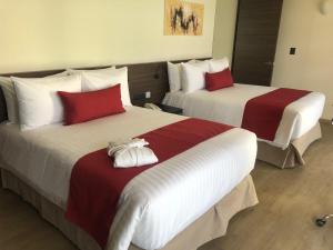 Dos camas en una habitación de hotel con rojo y blanco en MC Suites Mexico City, en Ciudad de México