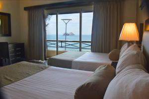 um quarto de hotel com duas camas e vista para o oceano em Hotel La Siesta em Mazatlán