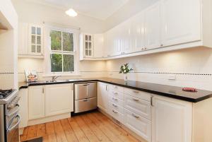 a white kitchen with white cabinets and a window at Poet's Cottage - Fireplace, Close to Treks in Wentworth Falls