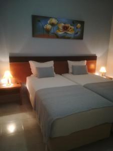 two beds in a hotel room with two lamps at Casa Luar in Odeceixe