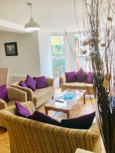 a living room with couches and a table and purple pillows at Runnacleave Court, apartment 2 in Ilfracombe