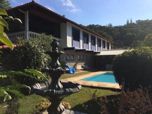 uma fonte em frente a uma casa com piscina em Bela e Aconchegante Casa em Itaipava em Petrópolis